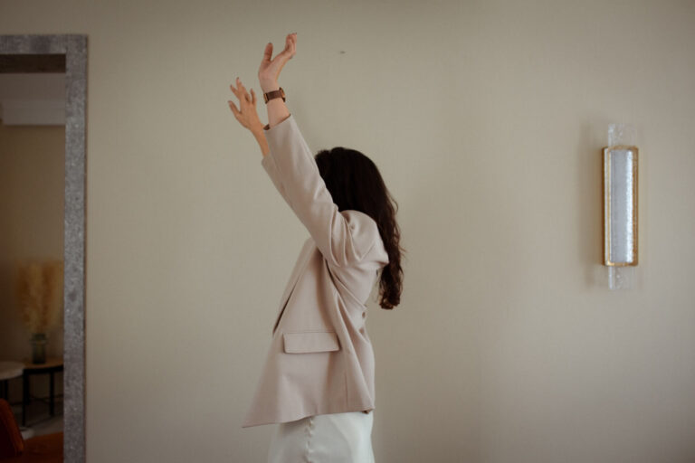 Woman-holds-hands-above-head-wearing-beige-blazer-thaifolk-studio-finding-client